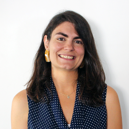 Portrait shot of Maria Azevedo, a woman with long, dark hair and dark eyes. She is smiling and wearing a sleeveless top.