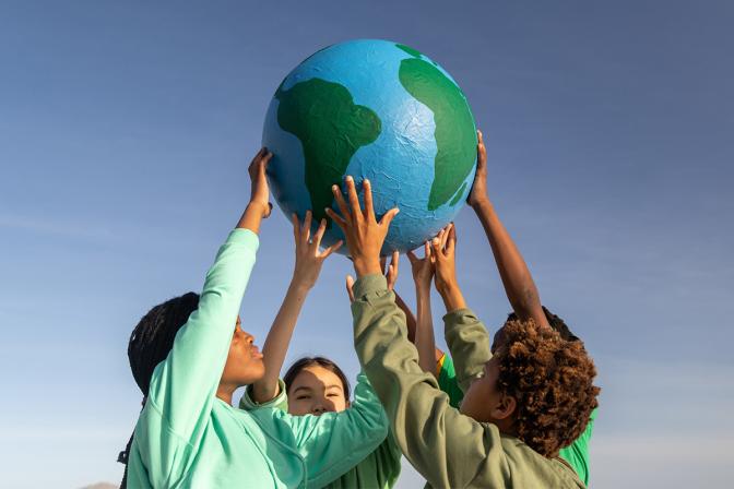 children holding up paper mache globe