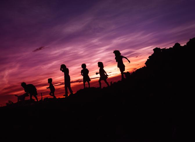 silohuettes kids on hill at sunset
