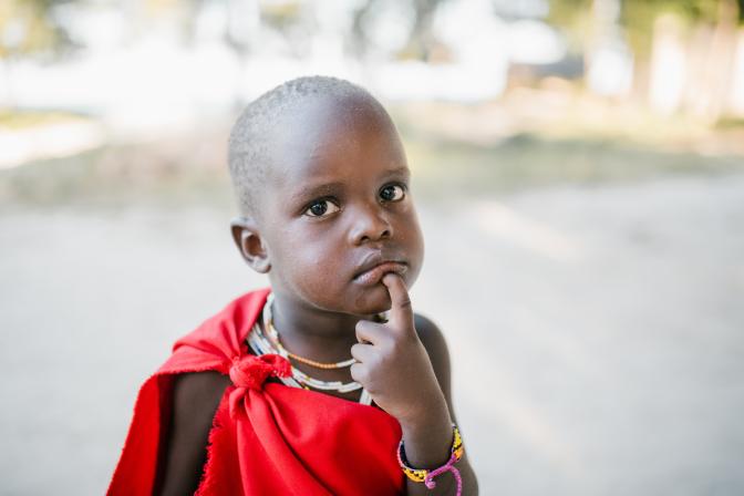 kid touching chin on local town street