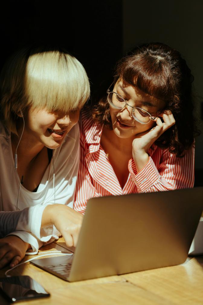 Two women are happily looking at a laptop screen together