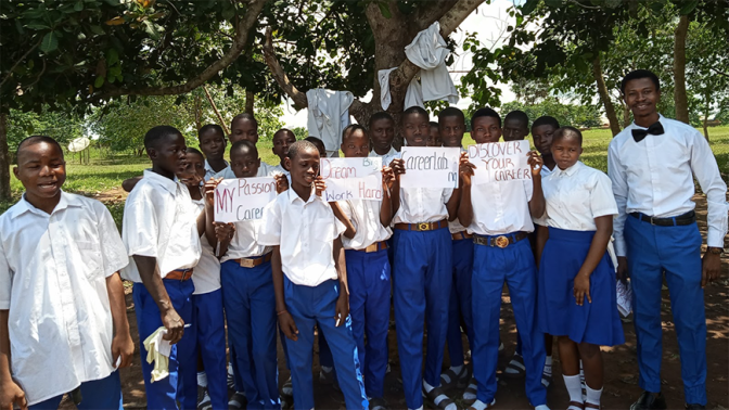 Nigerian students in school uniform outside holding inspirational messages on paper