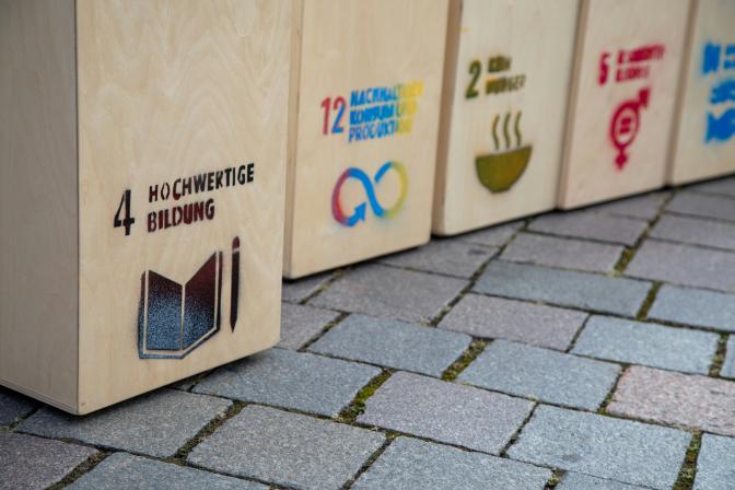 a row of wooden boxes with SDG prints, sitting on top of a sidewalk