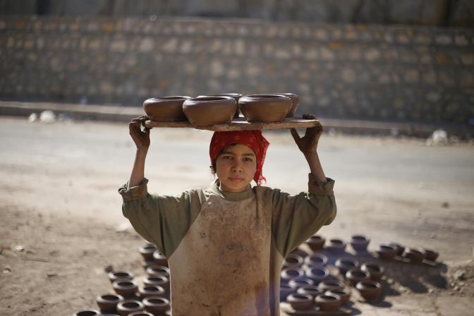 a child carrying potteries on the head