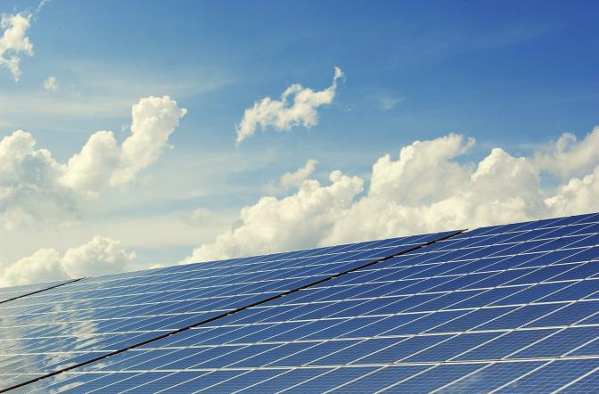 solar panels underneath a blue sky with white clouds