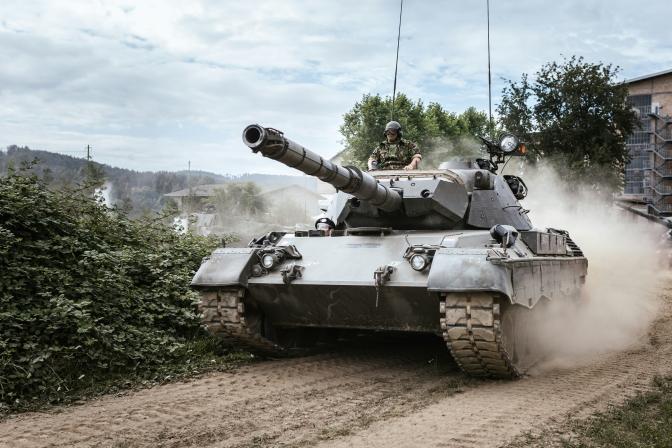 Soldier riding a military tank going down a dirt path