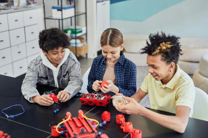 Three children sitting down and doing robotics together