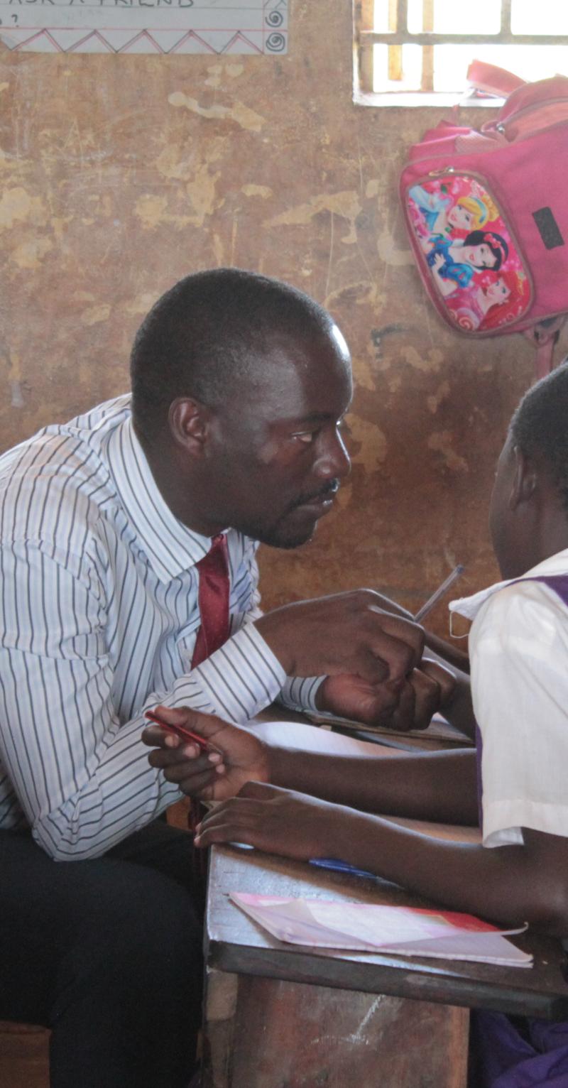 Teach For Uganda teacher sitting and guiding his students