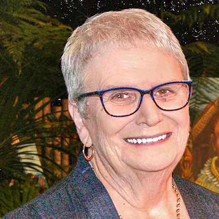 Portrait shot of Ann Milne, a woman with short hair wearing glasses. She is looking at the camera and smiling.